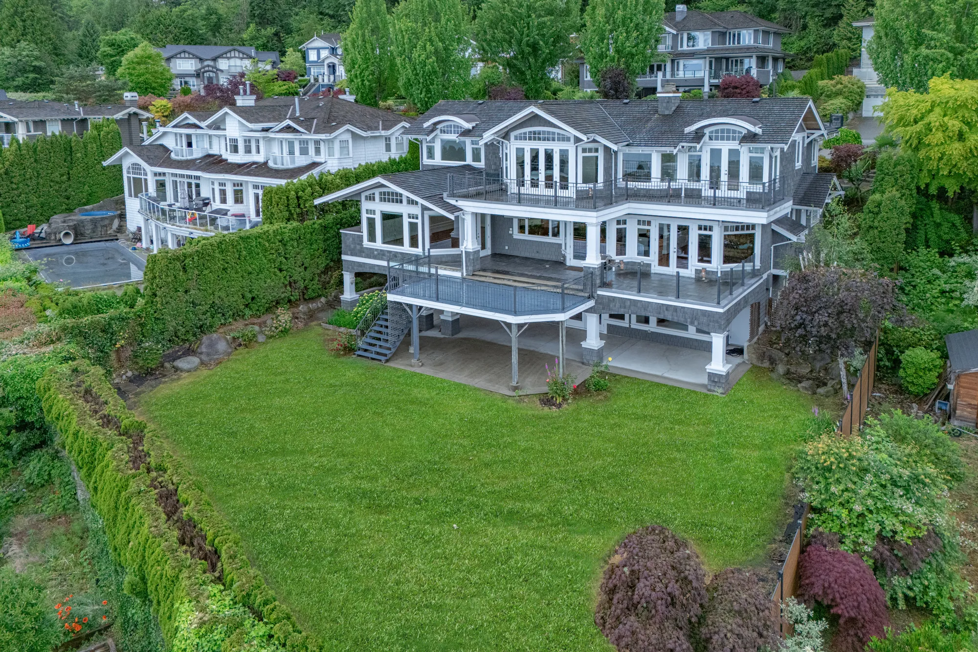 The property from the side, the hedged lawn and the neighbouring houses stepping down the slope