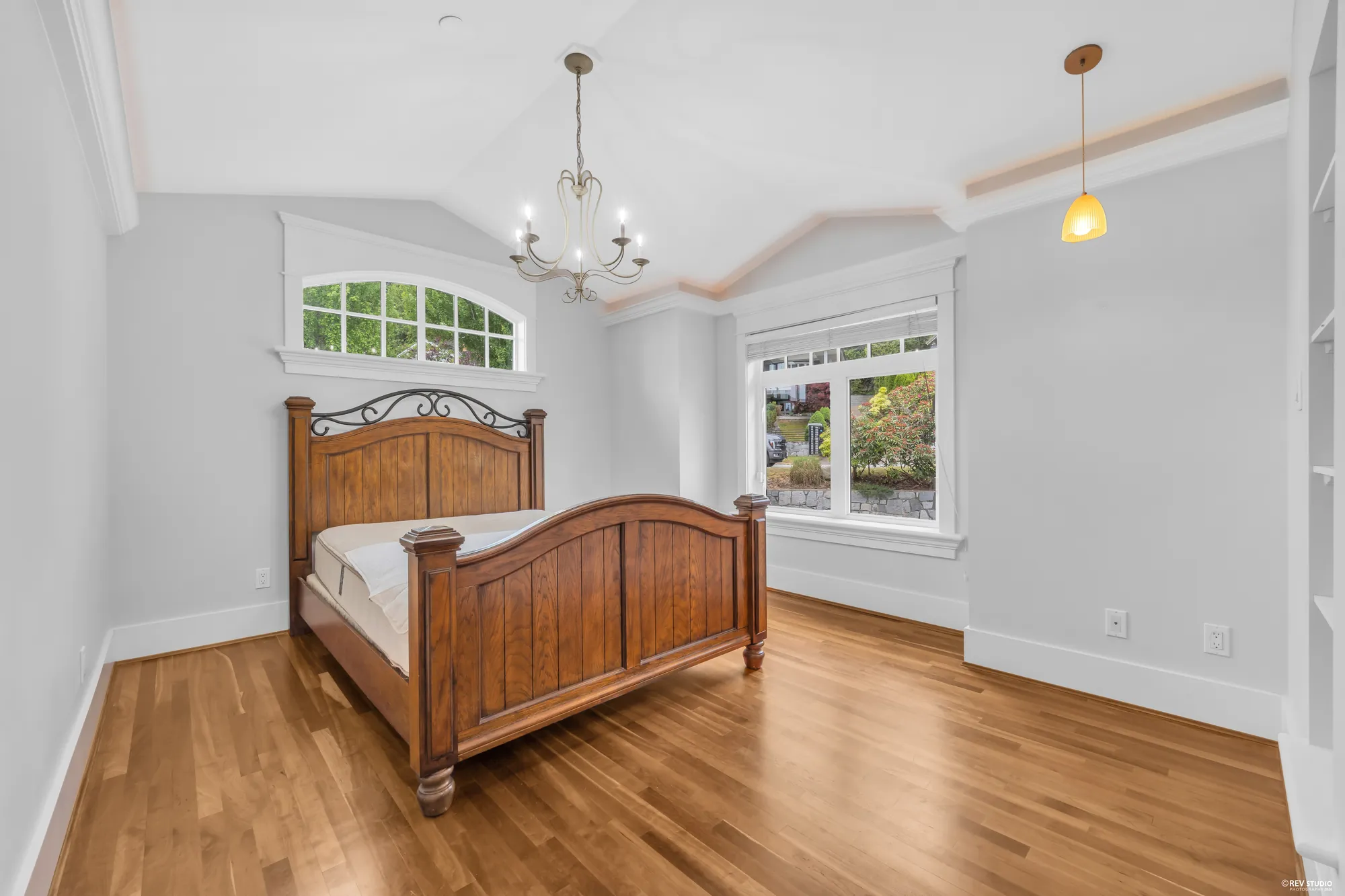 A bedroom with an arched transom over the window and a carved timber bed