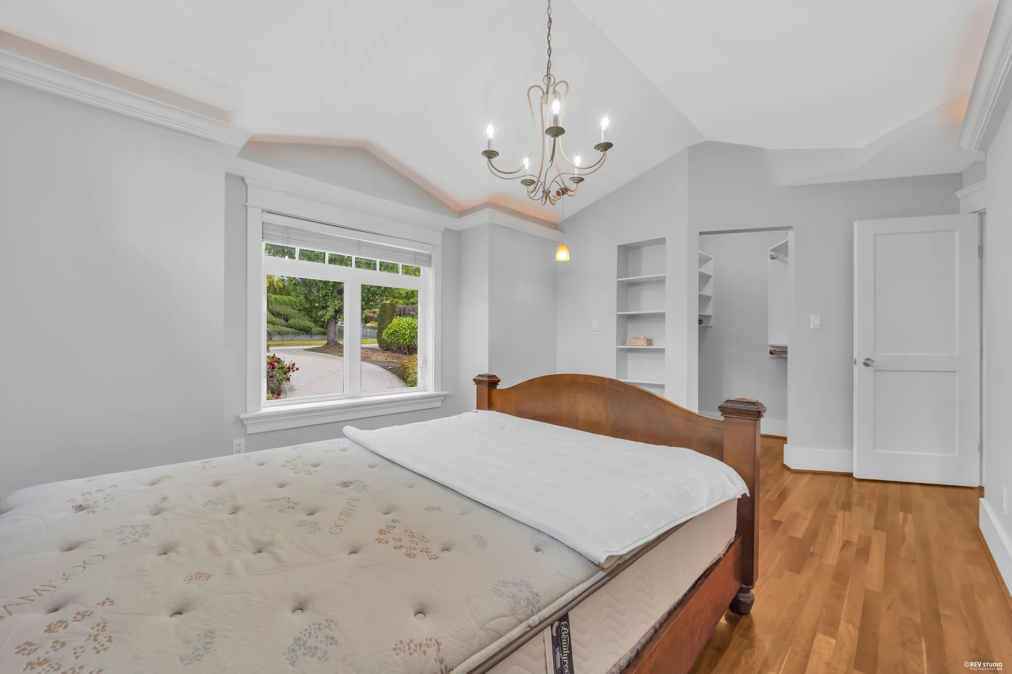 A bedroom with a window onto the trees and a built-in shelf beside the door