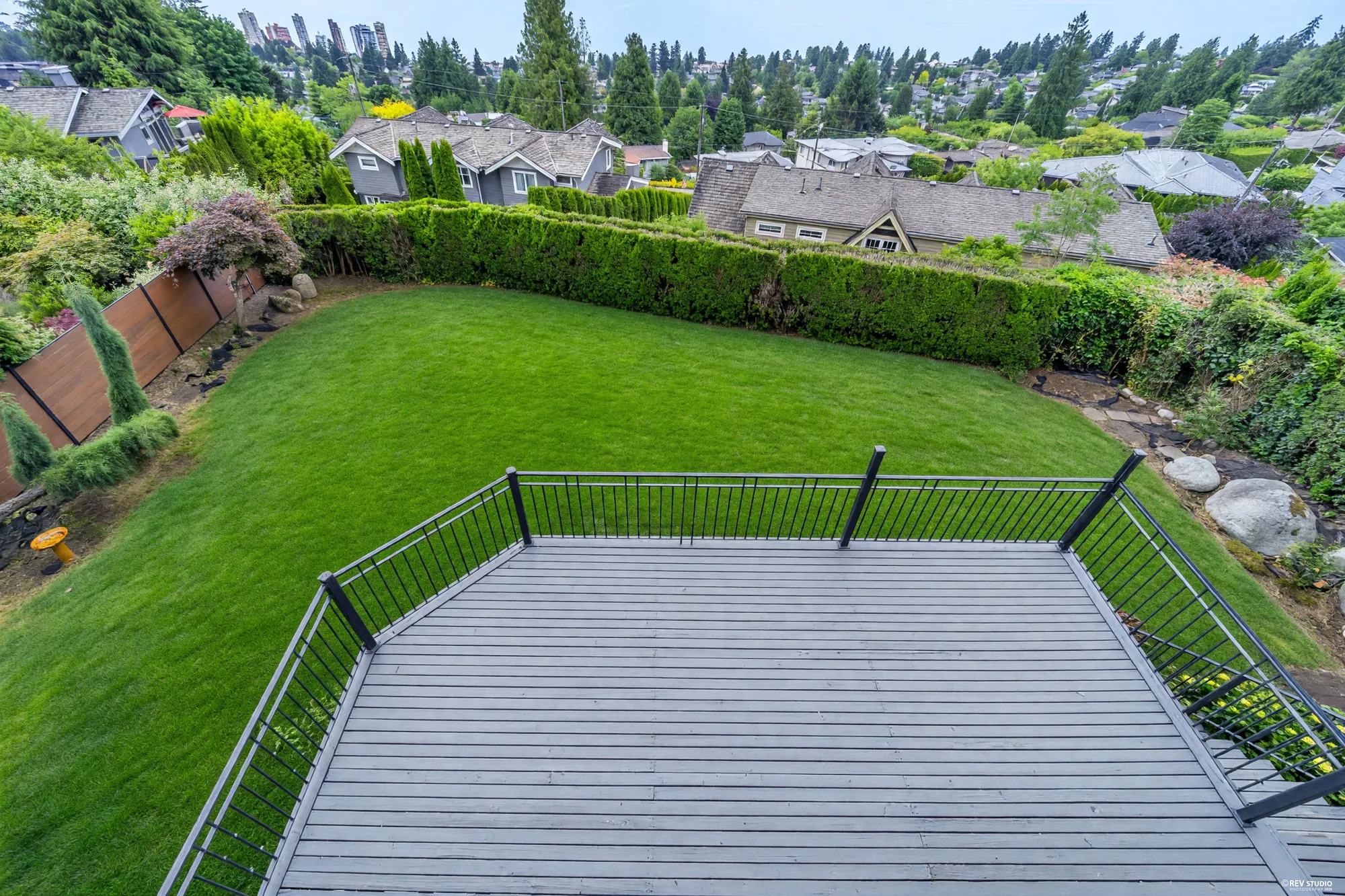 The composite deck at lawn level seen from above, fenced and set into the grass