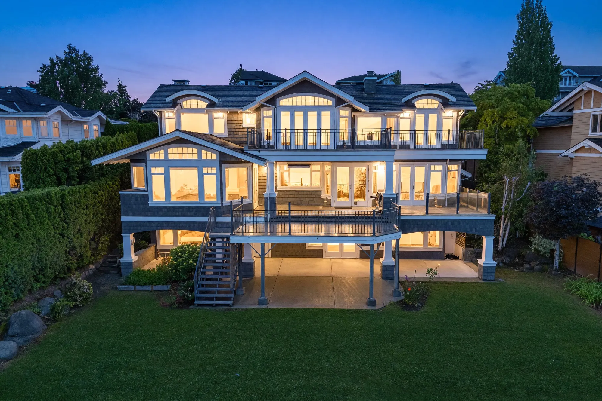 The back of the house from the air at dusk, the balconies lit and the lawn dark below