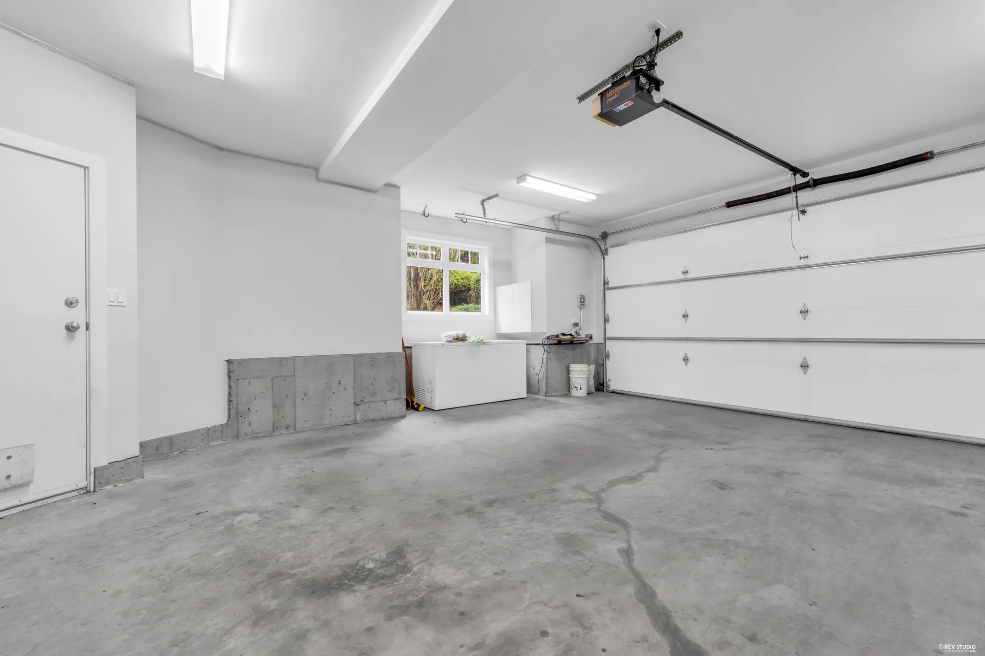 Inside the double garage looking at the doors, with a window on the side wall