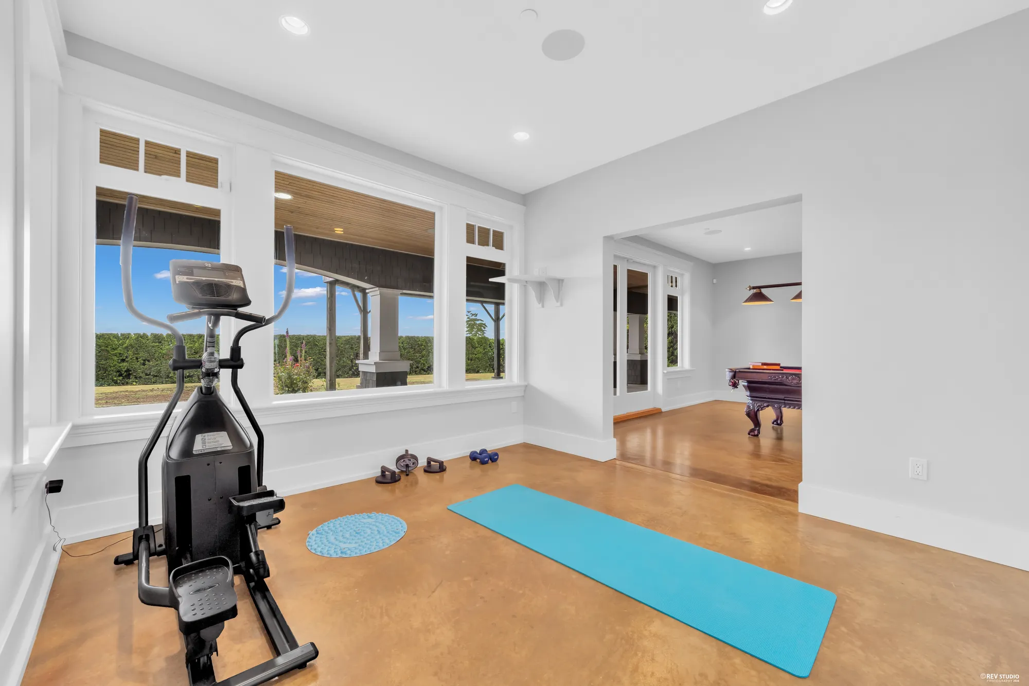 The gym at the window end with an exercise bike, a mat and free weights