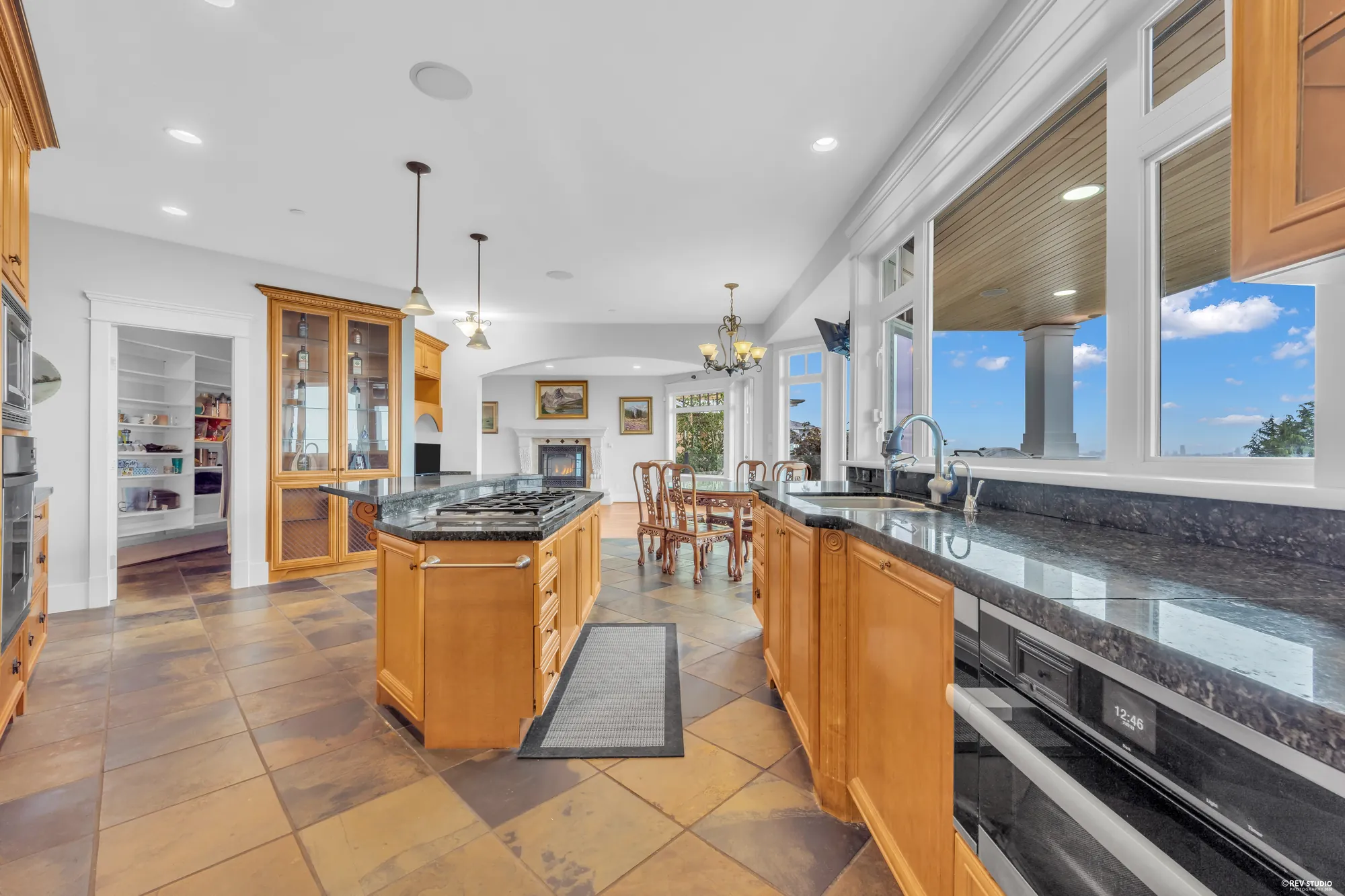 The kitchen work run with wall ovens, a warming drawer and granite counters under the windows