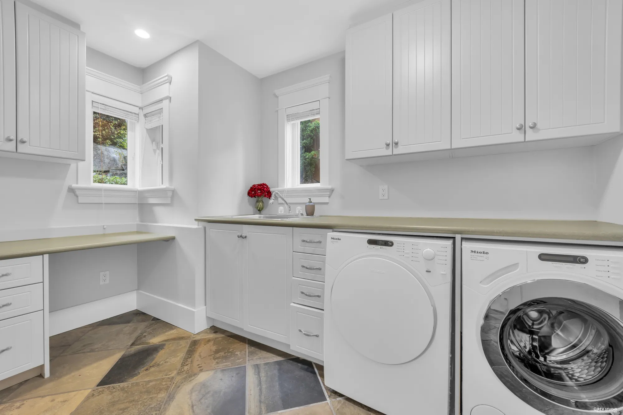 The main-floor laundry with a run of white cabinets, a counter and a front-loading washer