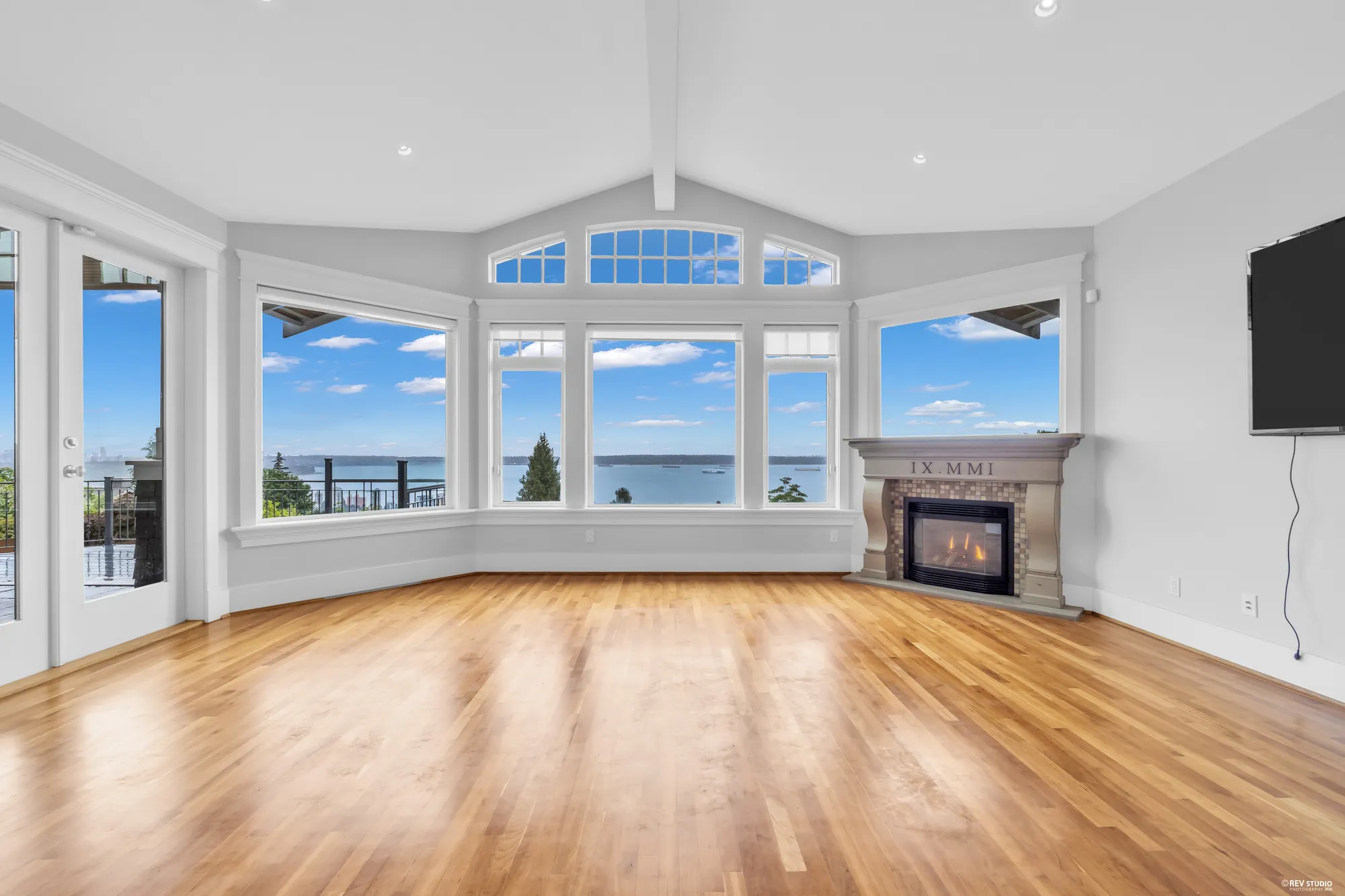 The family room fireplace in a stone surround with a bay of windows to its right