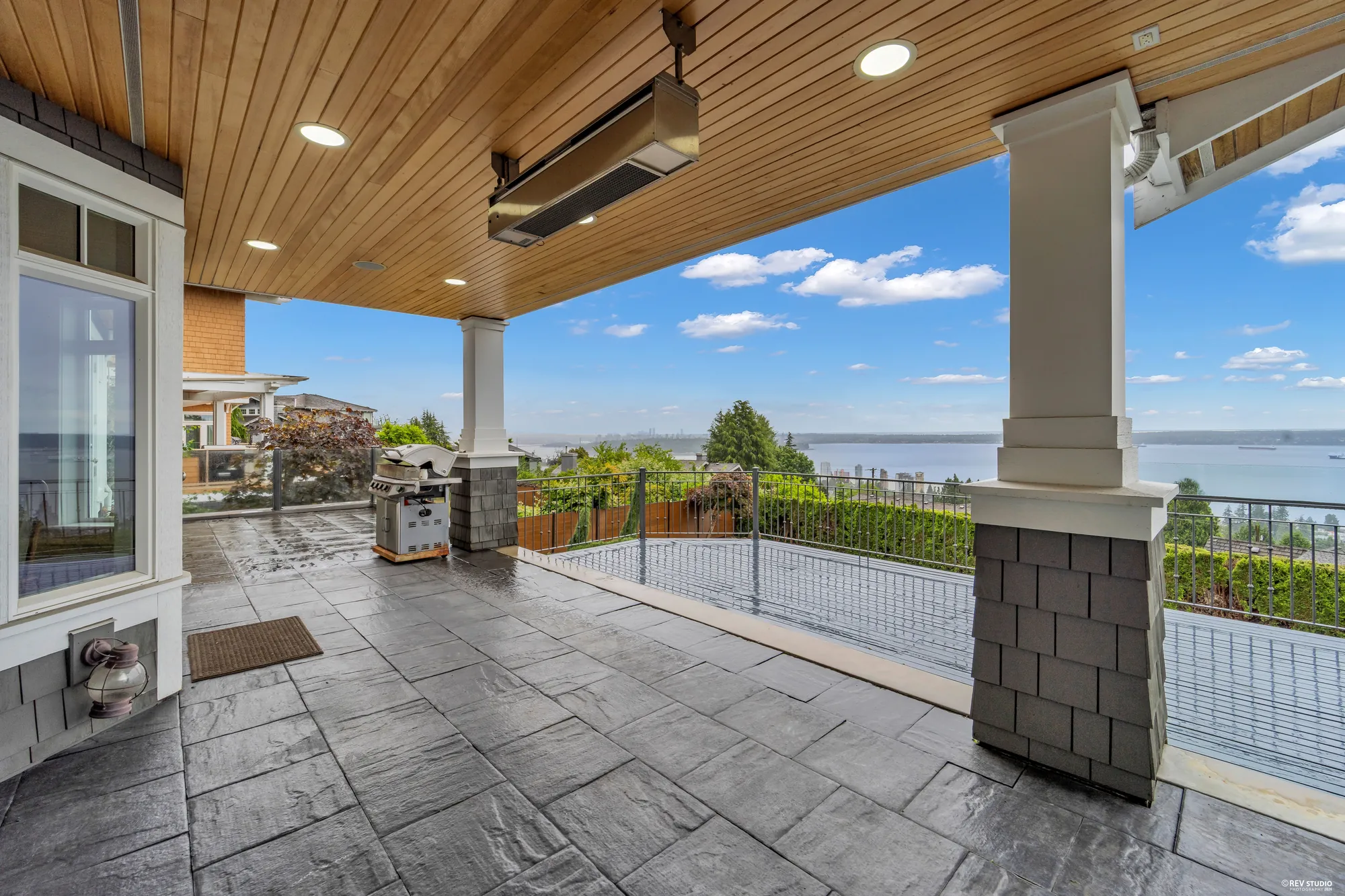 Under the cedar-lined loggia, the columns framing the water and a barbecue against the wall