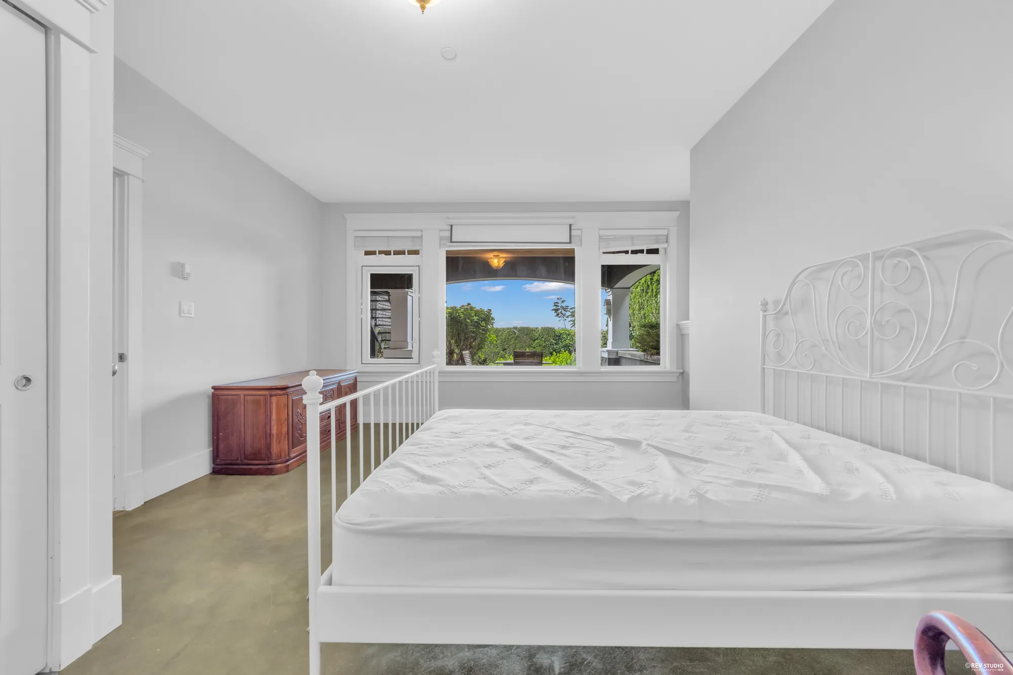 The lower bedroom with a window seat, a bed frame and the window onto the garden