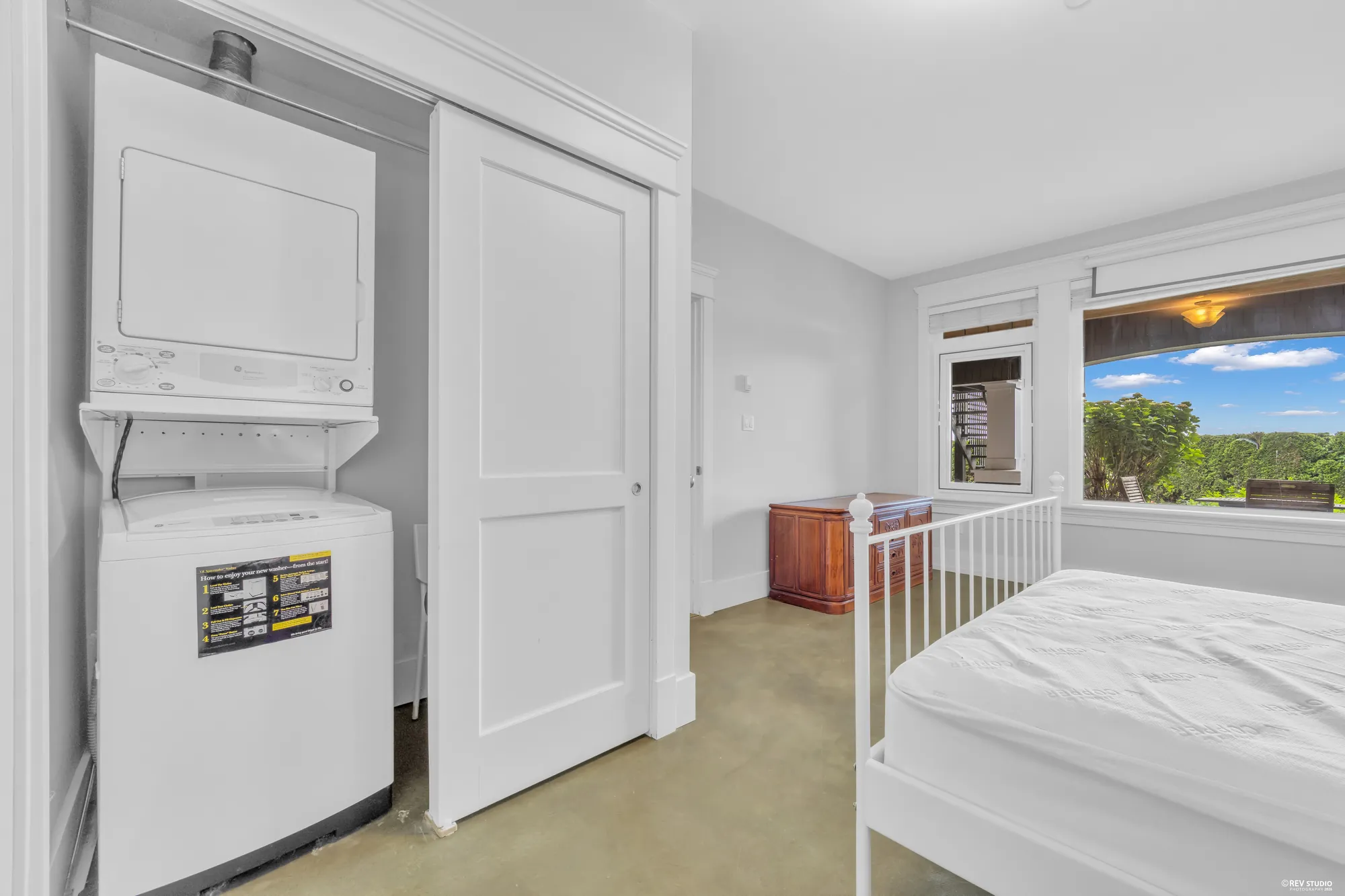 A stacked washer and dryer beside the lower bedroom door
