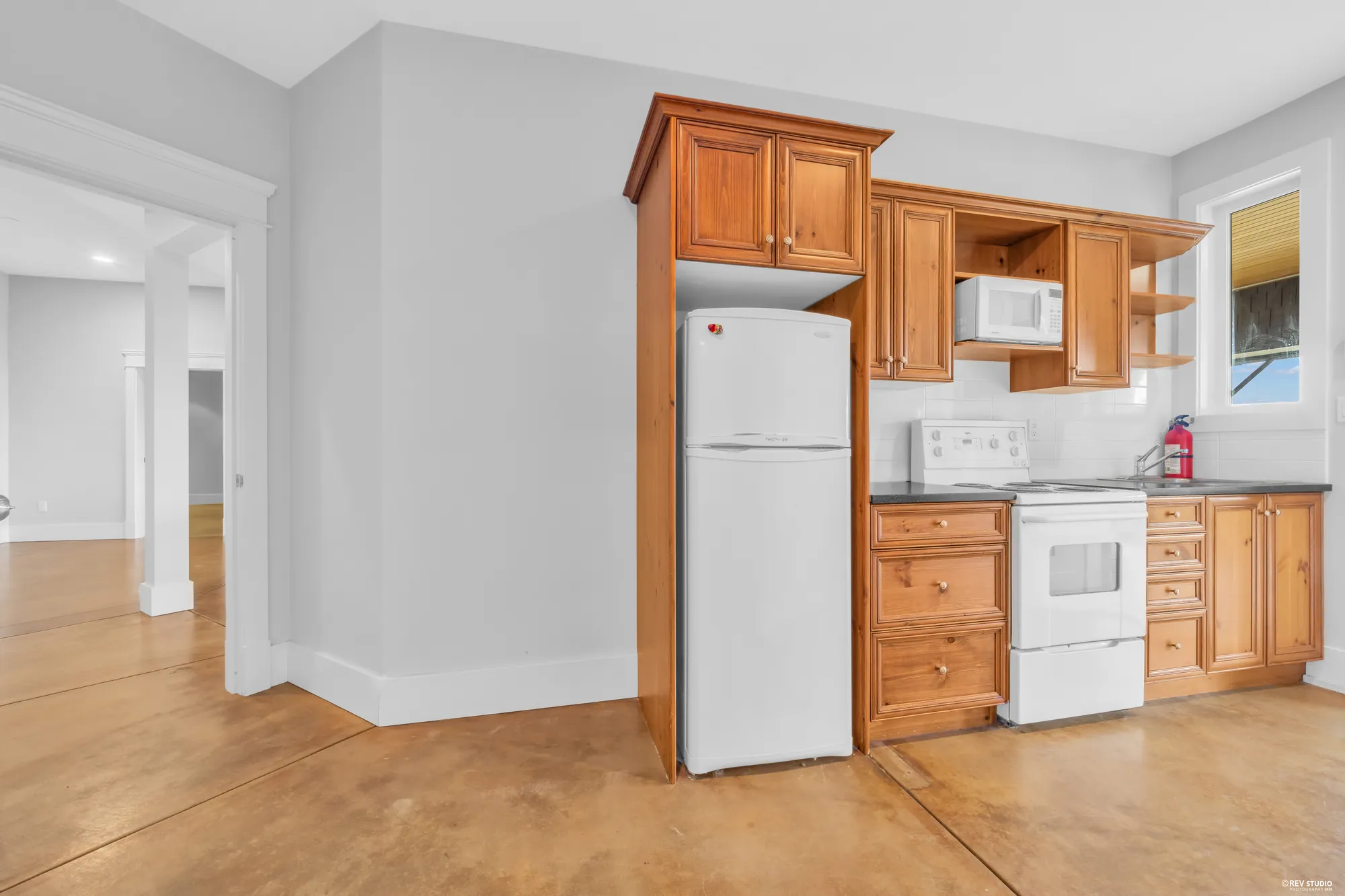 The second kitchen on the lower floor with maple cabinets, a white range and a fridge