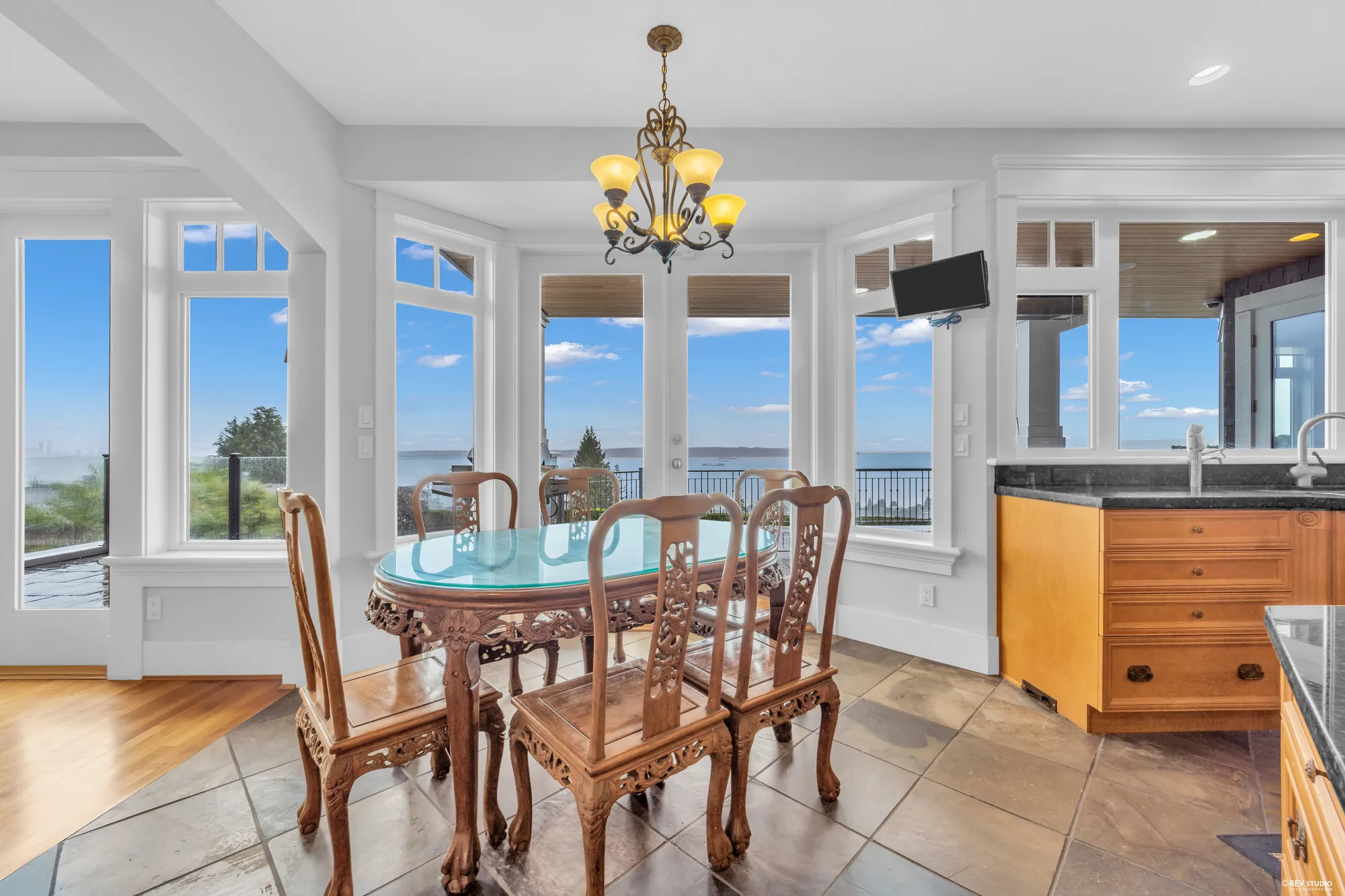 The breakfast nook in a bay of windows with a glass-topped table and the water behind it
