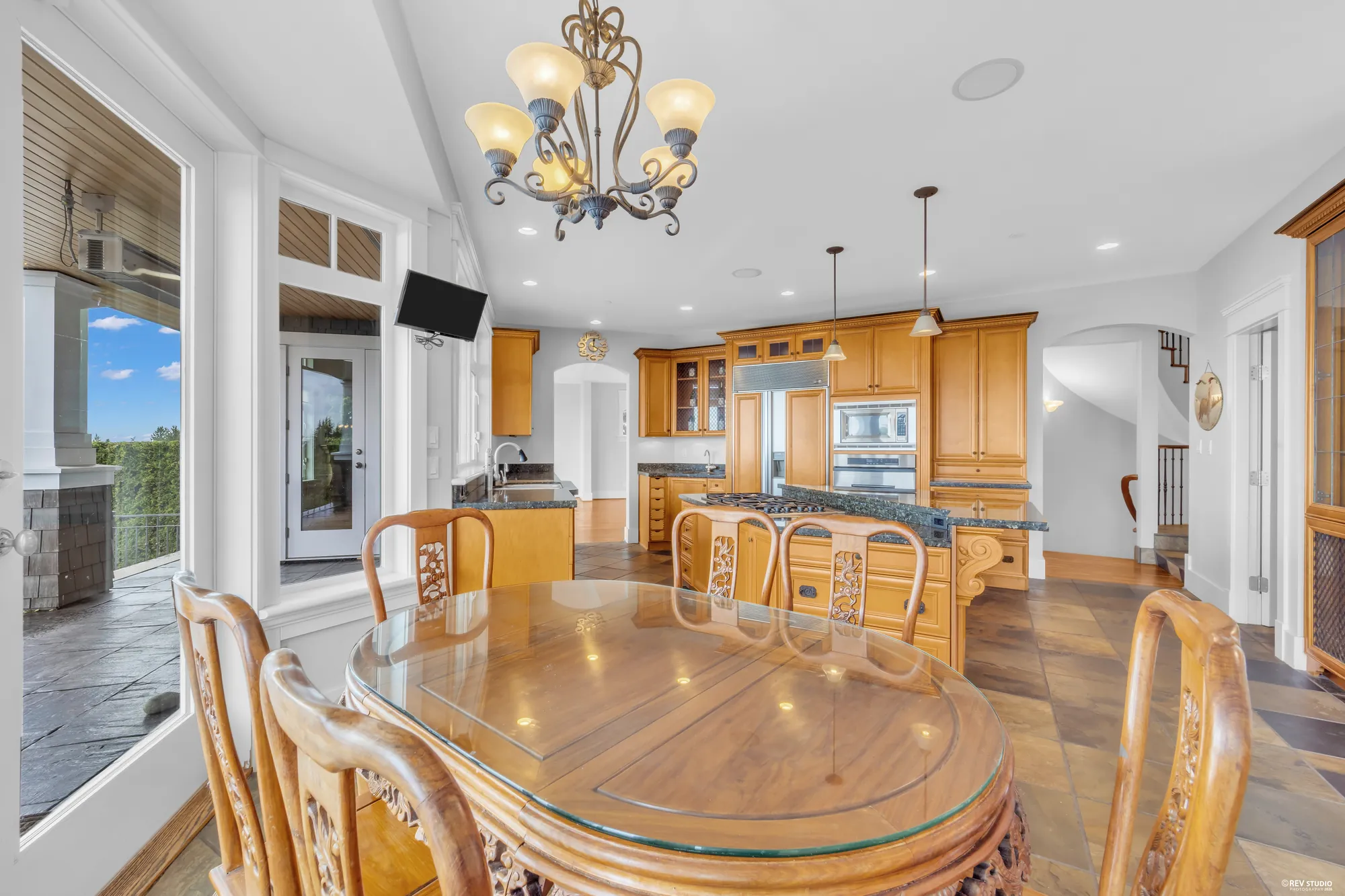The nook table from the kitchen side, the chandelier above and the balcony doors beyond