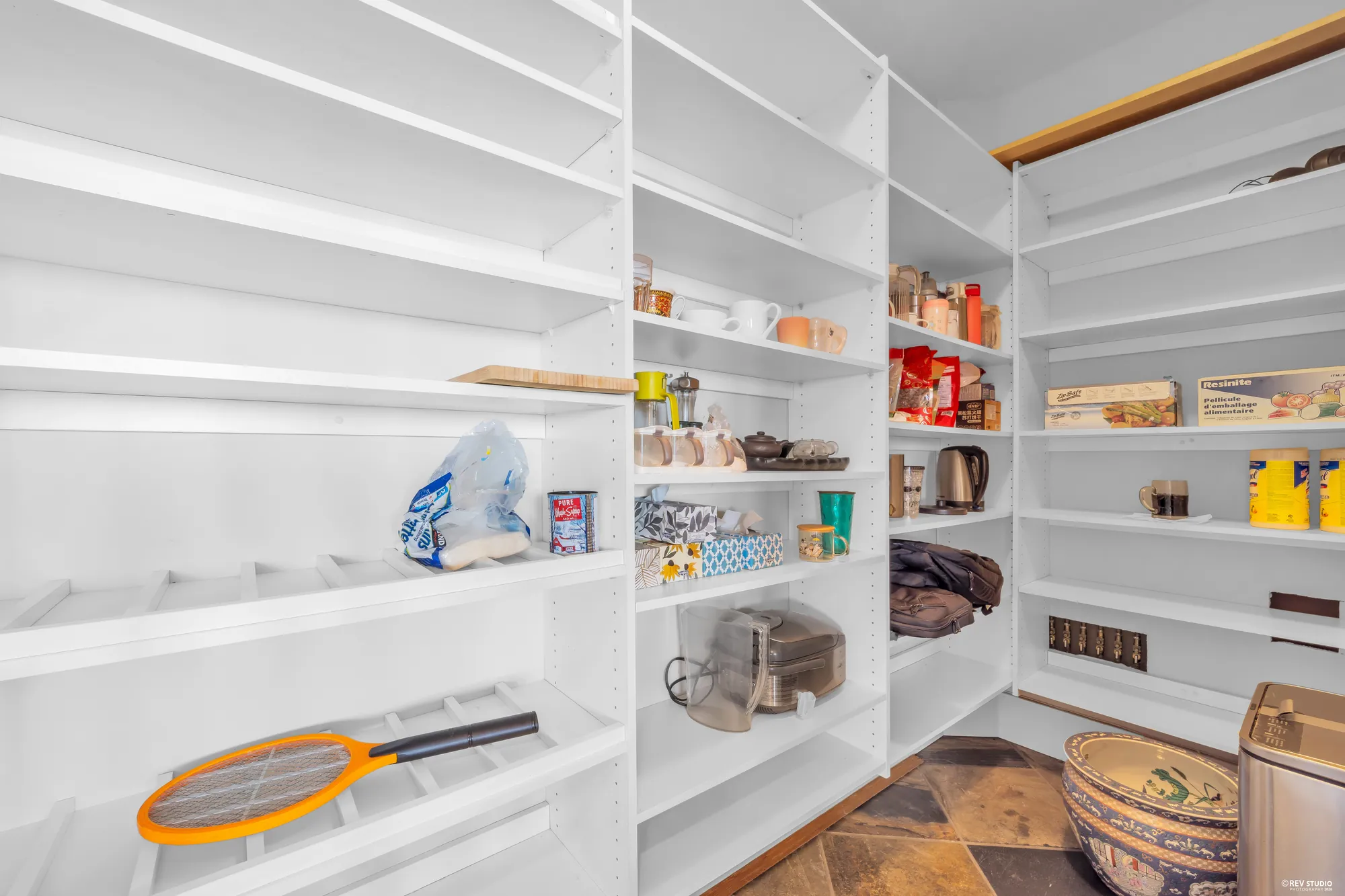 The walk-in pantry lined with white shelving on three sides