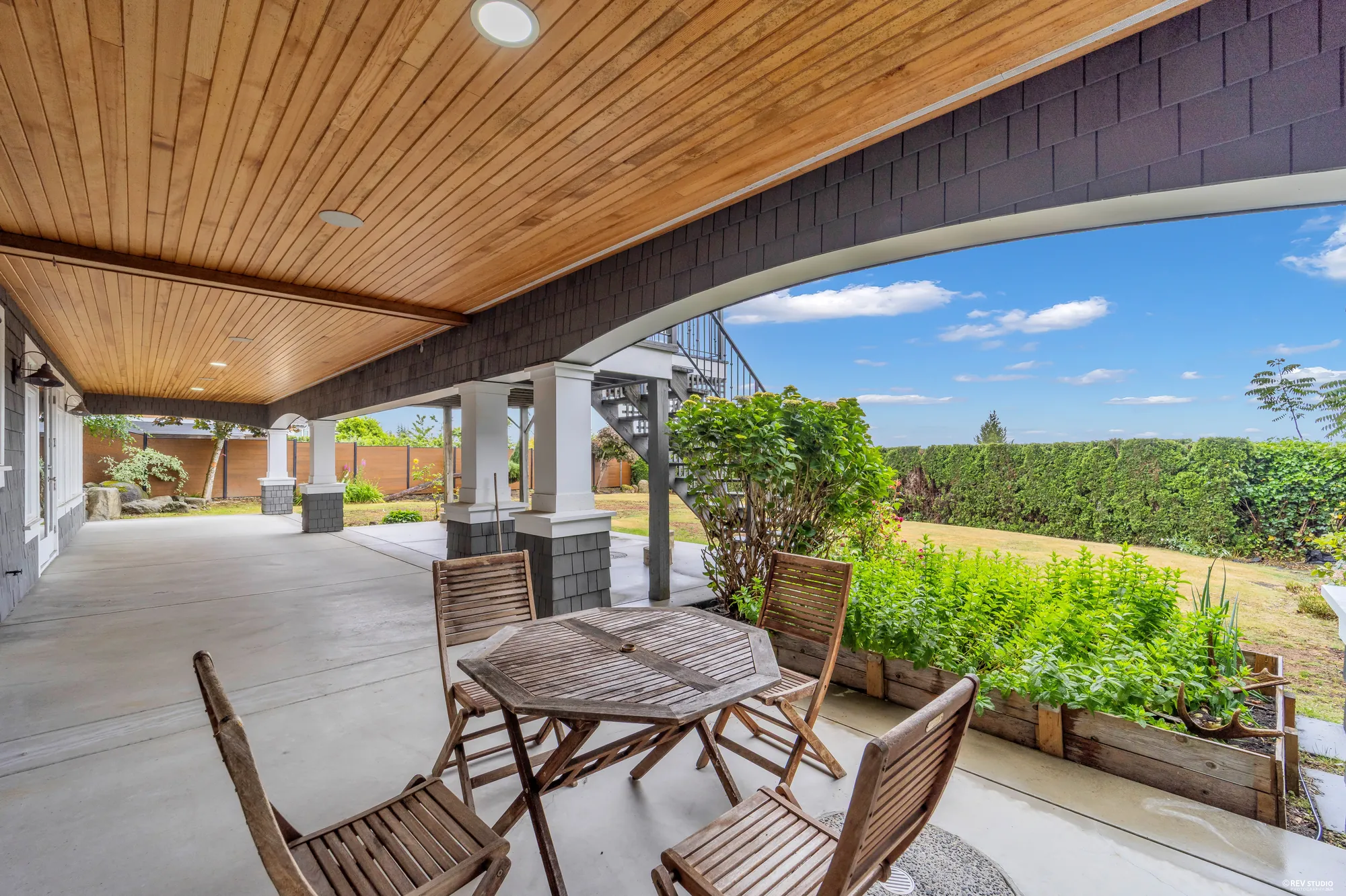 The lower covered patio with garden furniture, opening onto the lawn