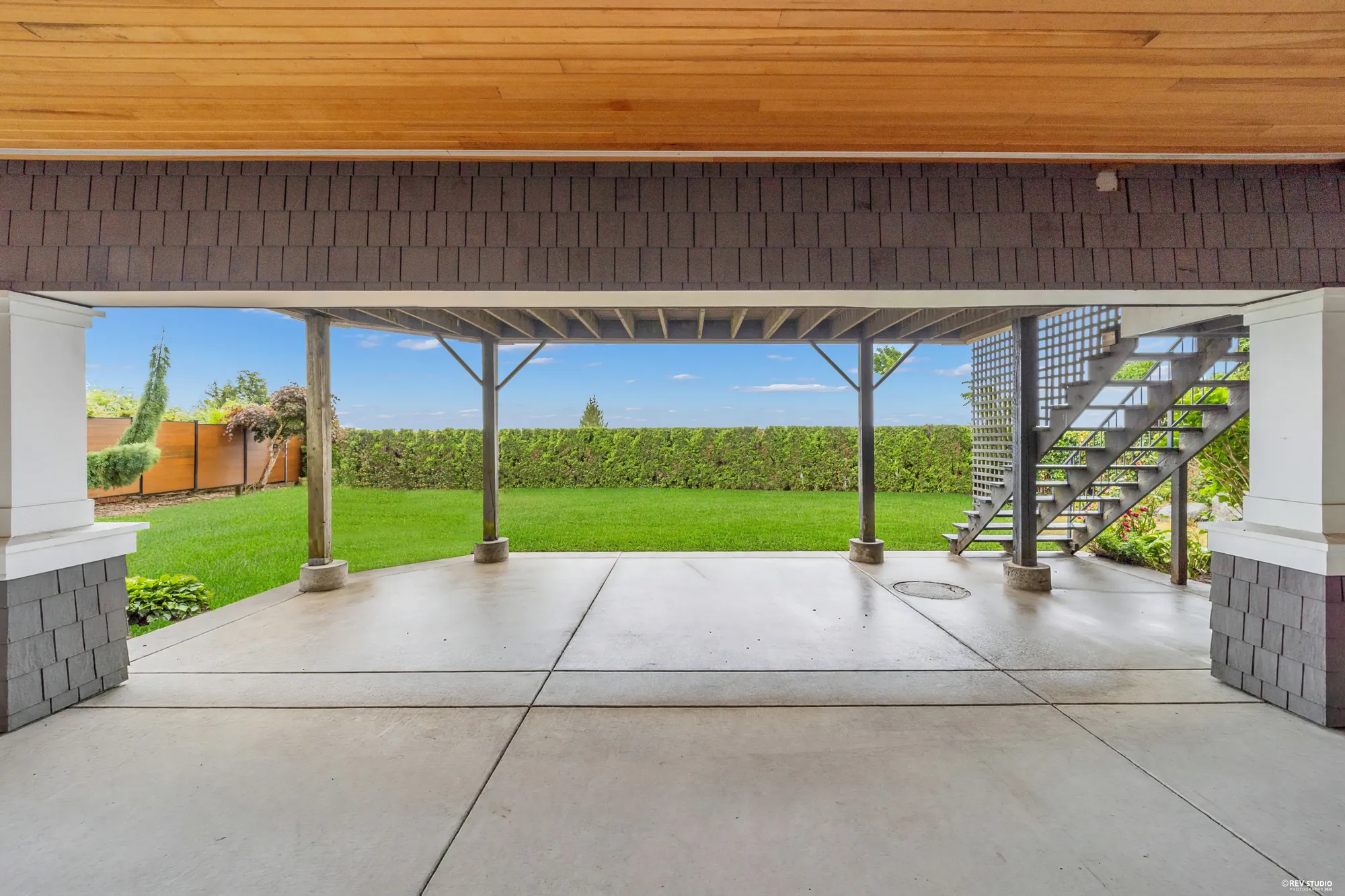 The lower patio between its columns, the stair up to the deck at the far side