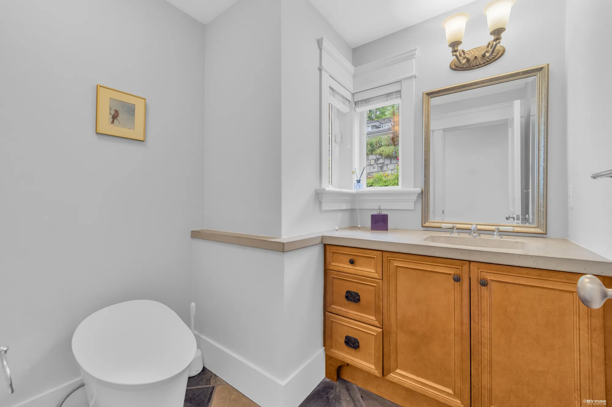 The powder room with a maple vanity, a granite top and a framed mirror