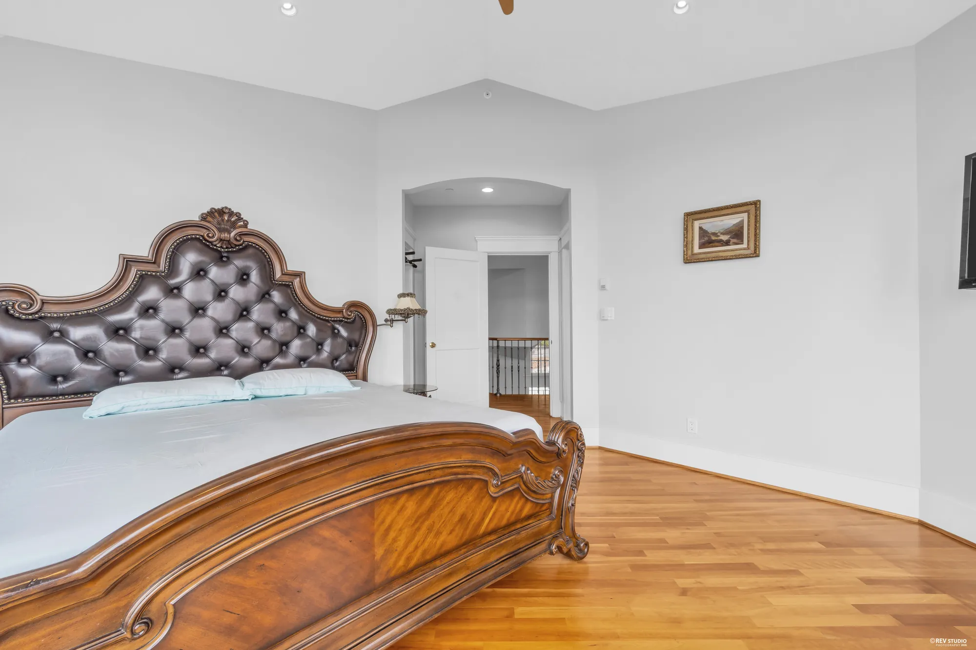 The primary bedroom from the window side, a carved timber bed against the far wall