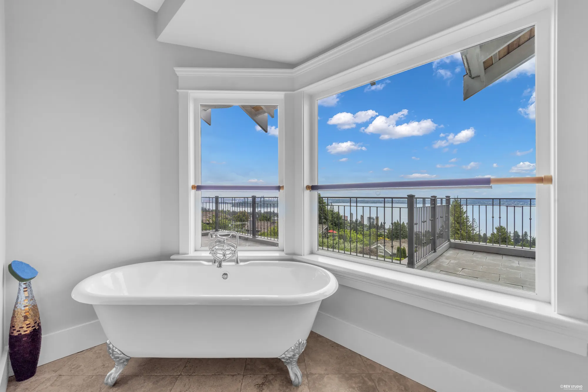 The clawfoot tub standing in a bay window with the water beyond the glass
