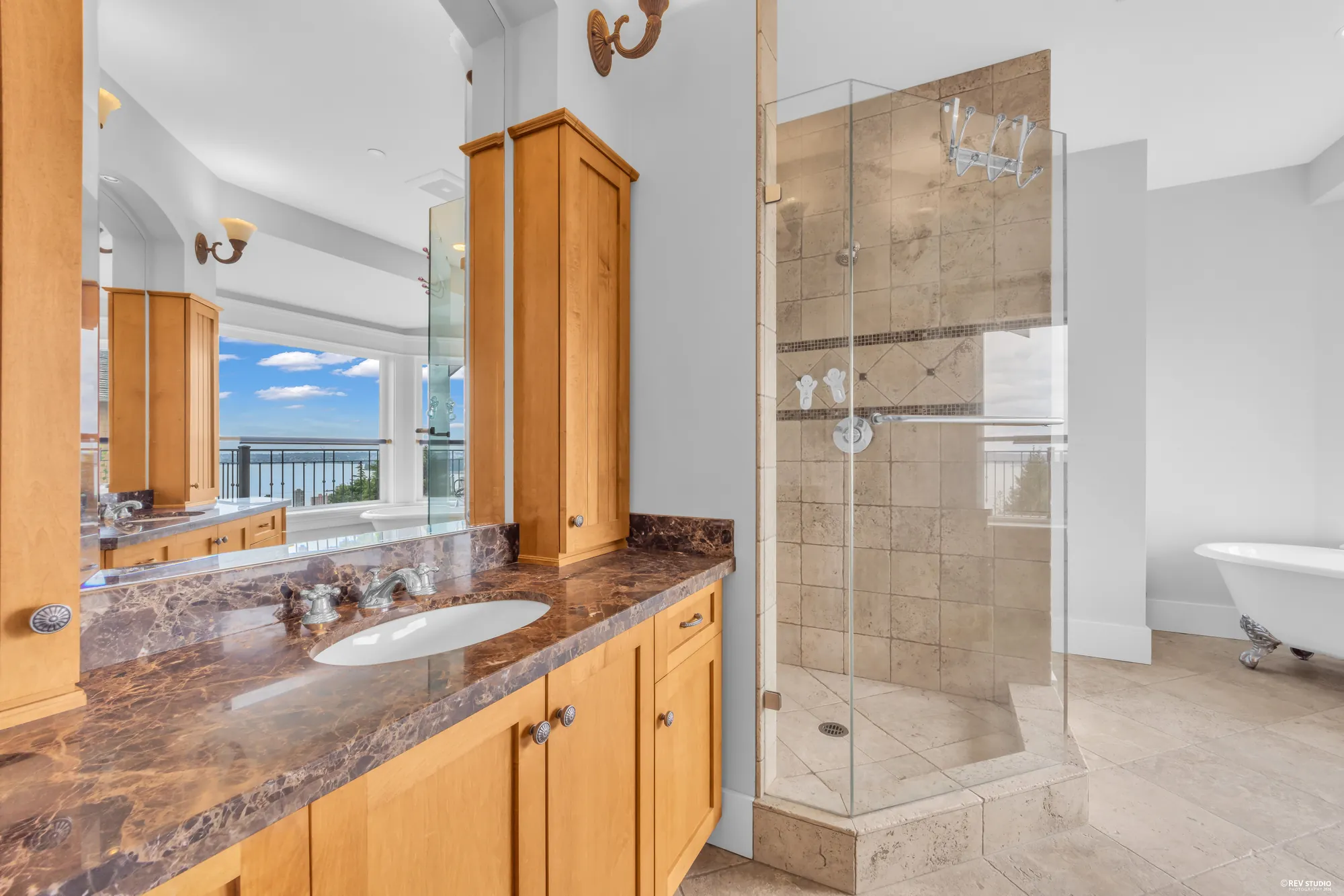 The bathroom vanity in granite under sconces, the shower enclosure to the right