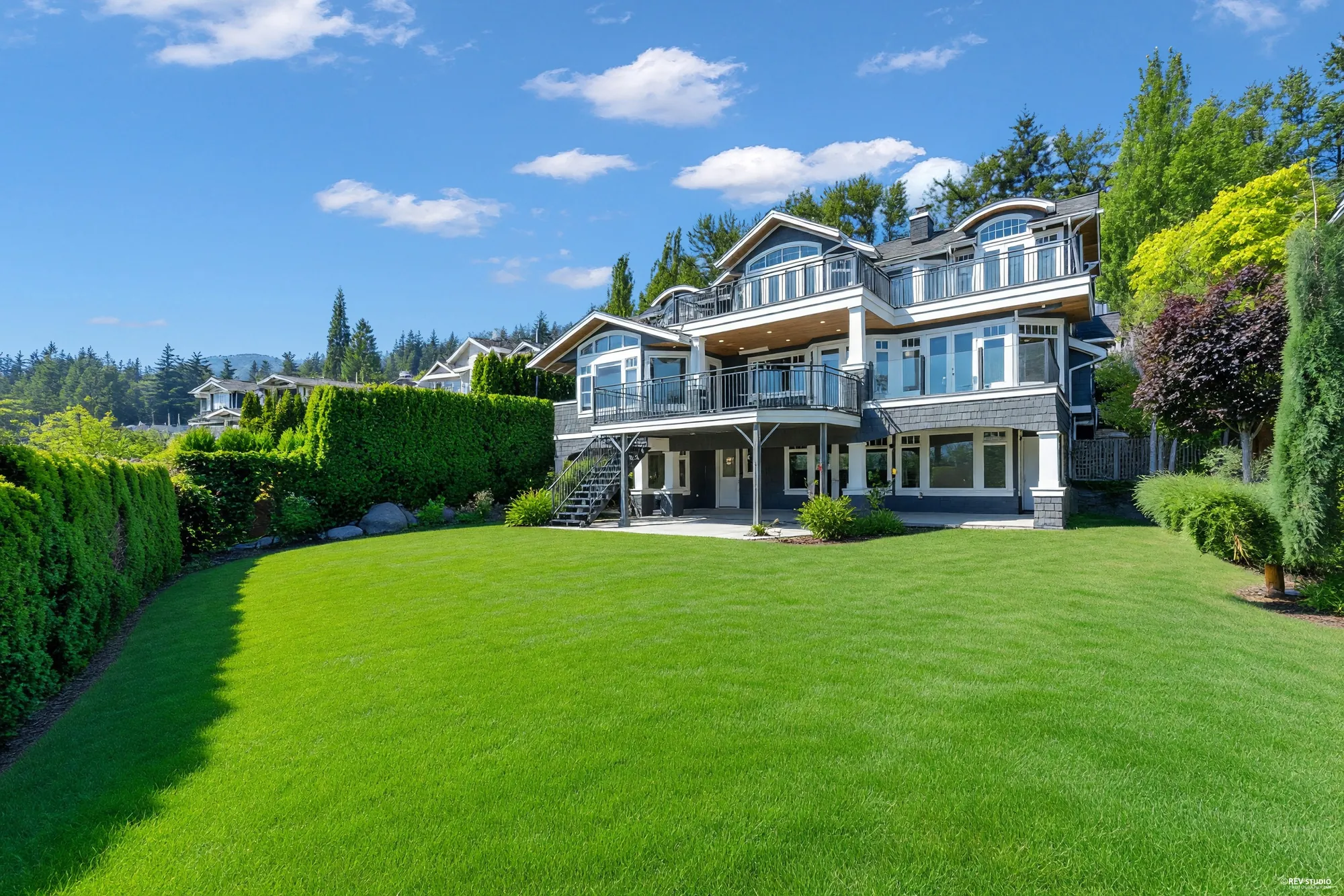 The house from the far corner of the lawn, the clipped boundary hedge running down one side