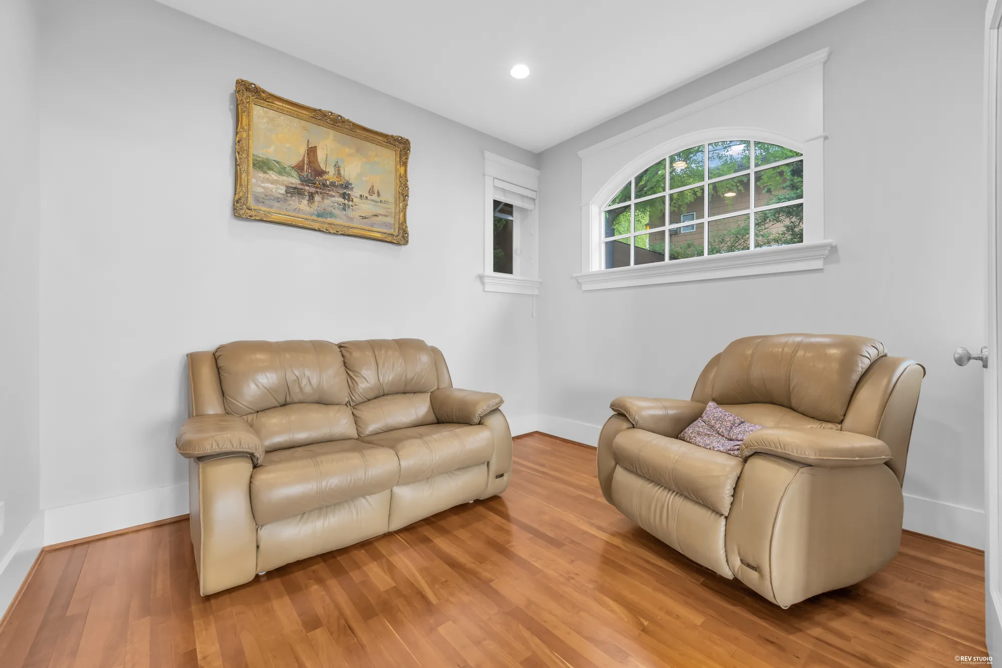 A sitting area with two leather recliners under a framed picture and a window onto the trees