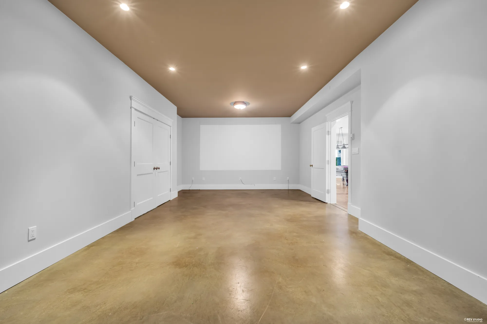 The theatre room, empty, with a projection wall at the far end and recessed lighting