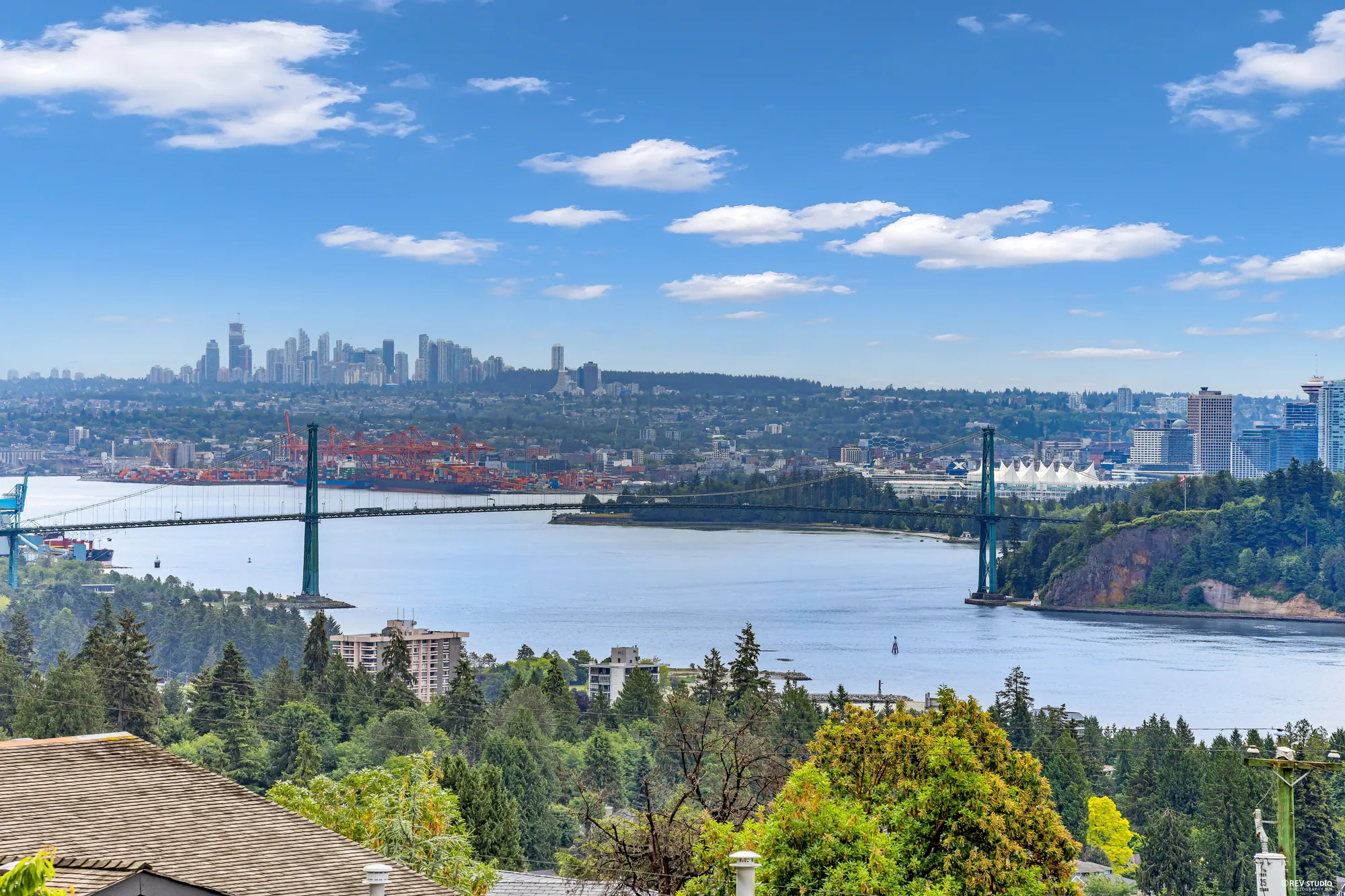 The downtown Vancouver skyline, Stanley Park and the Lions Gate Bridge seen across the water from the property, with freighters on the anchorage