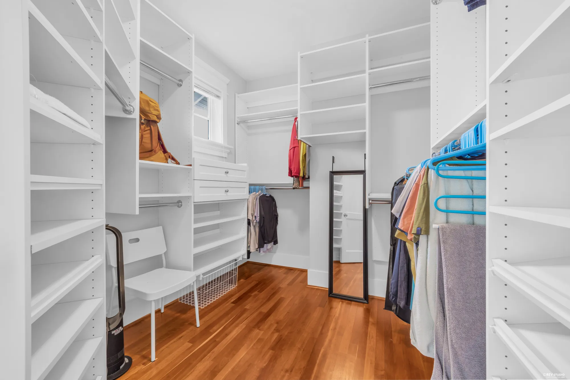 A second walk-in closet with open shelving and a window at the end
